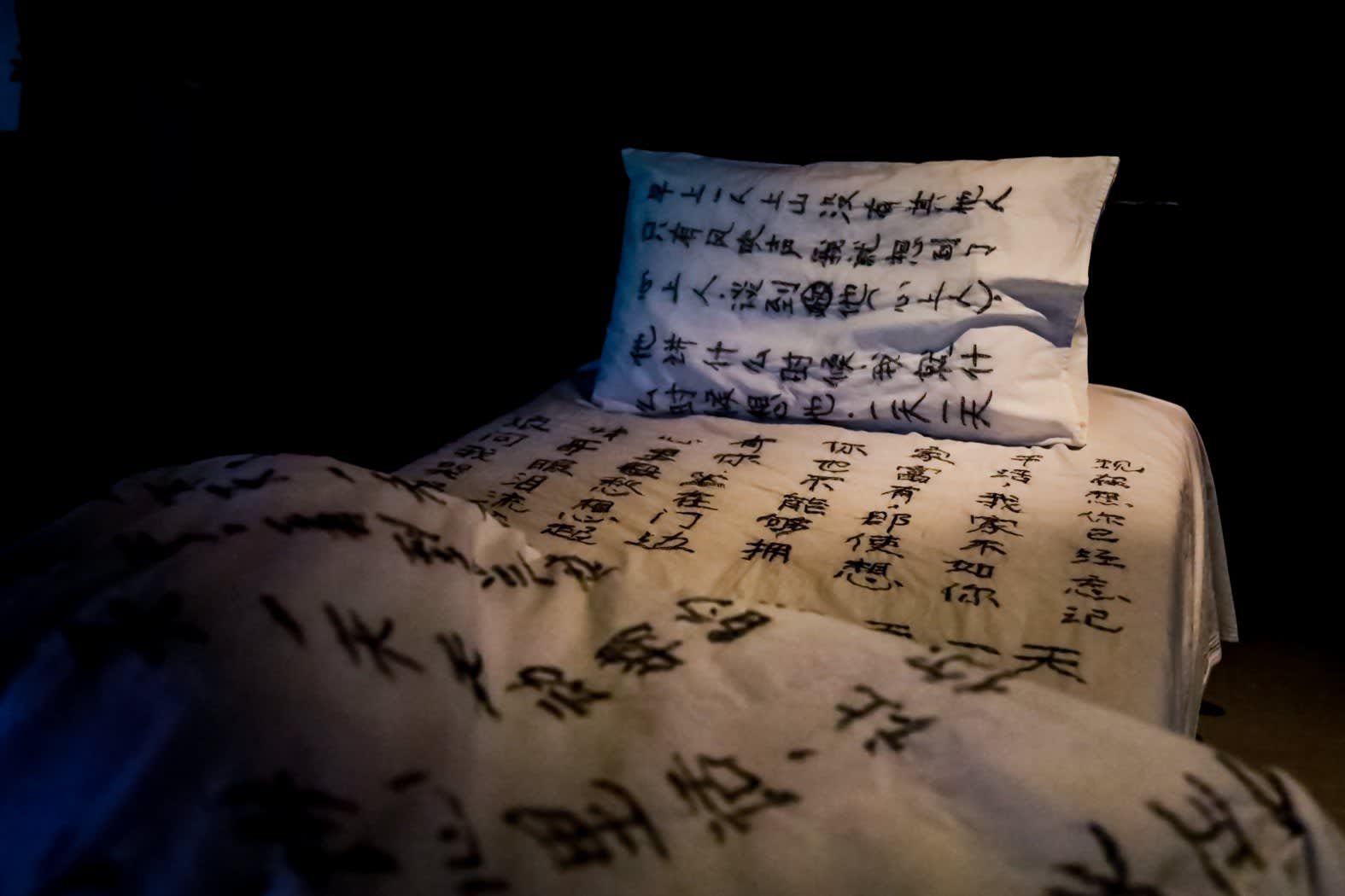 A shot of bed in white sheet with embroidery made by village women's hair.