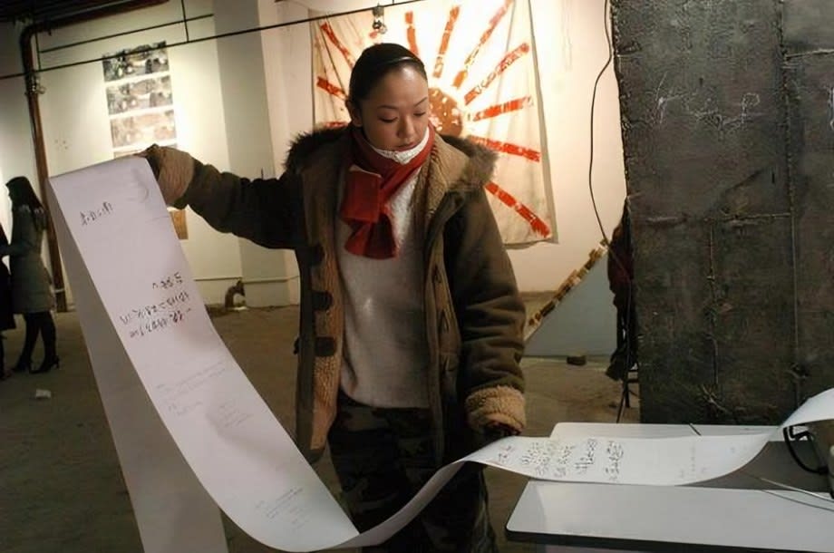Artist Chen Qiulin is pulling out the fax from the fax machine.