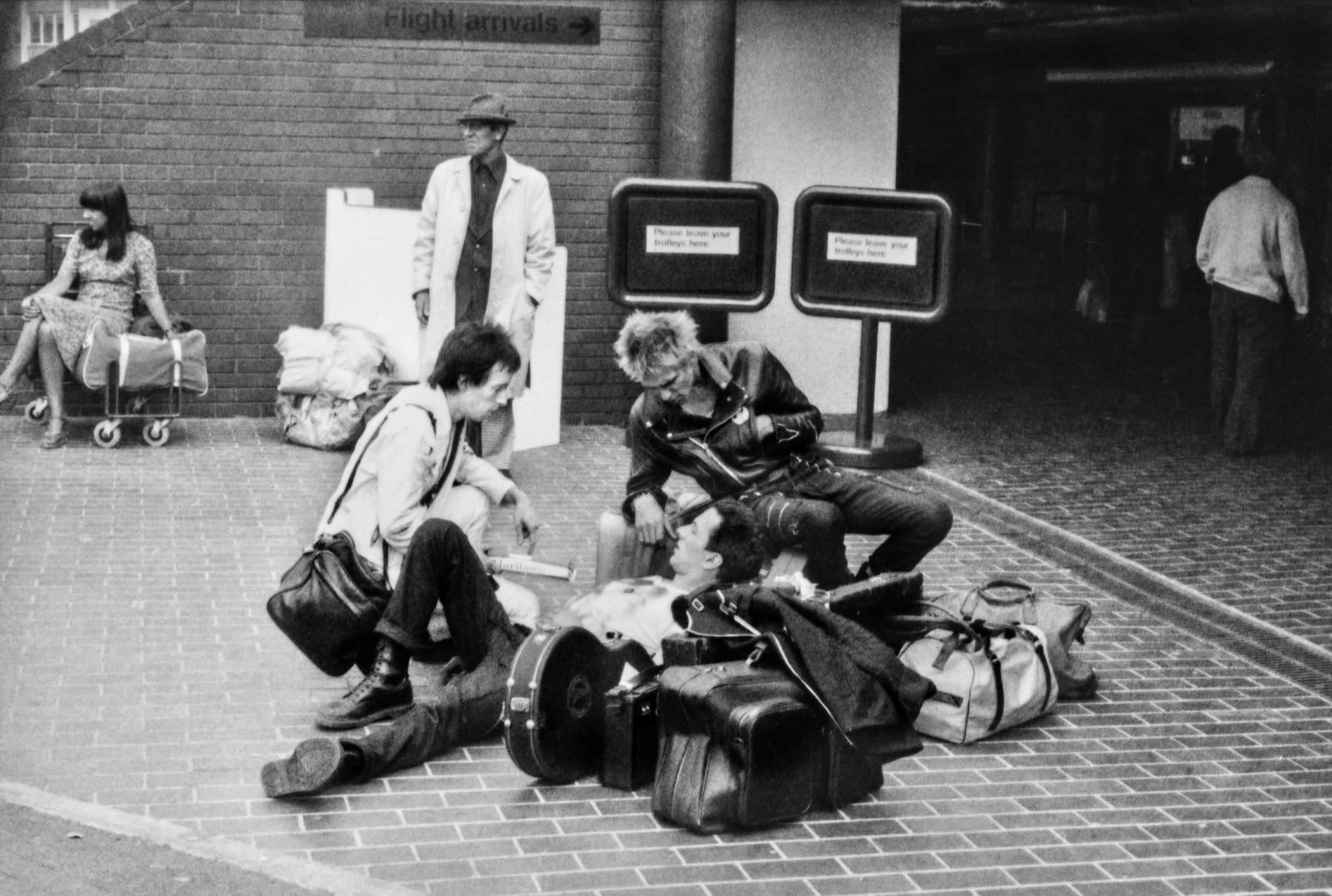 Caroline Coon, The Clash. On the road, Topper Headon (drums), Joe Strummer (lead singer/guitar) and Paul Simonon (bass) at Heathrow airport on the way to The Second European Punk Rock Festival, South of France. August, 1977
