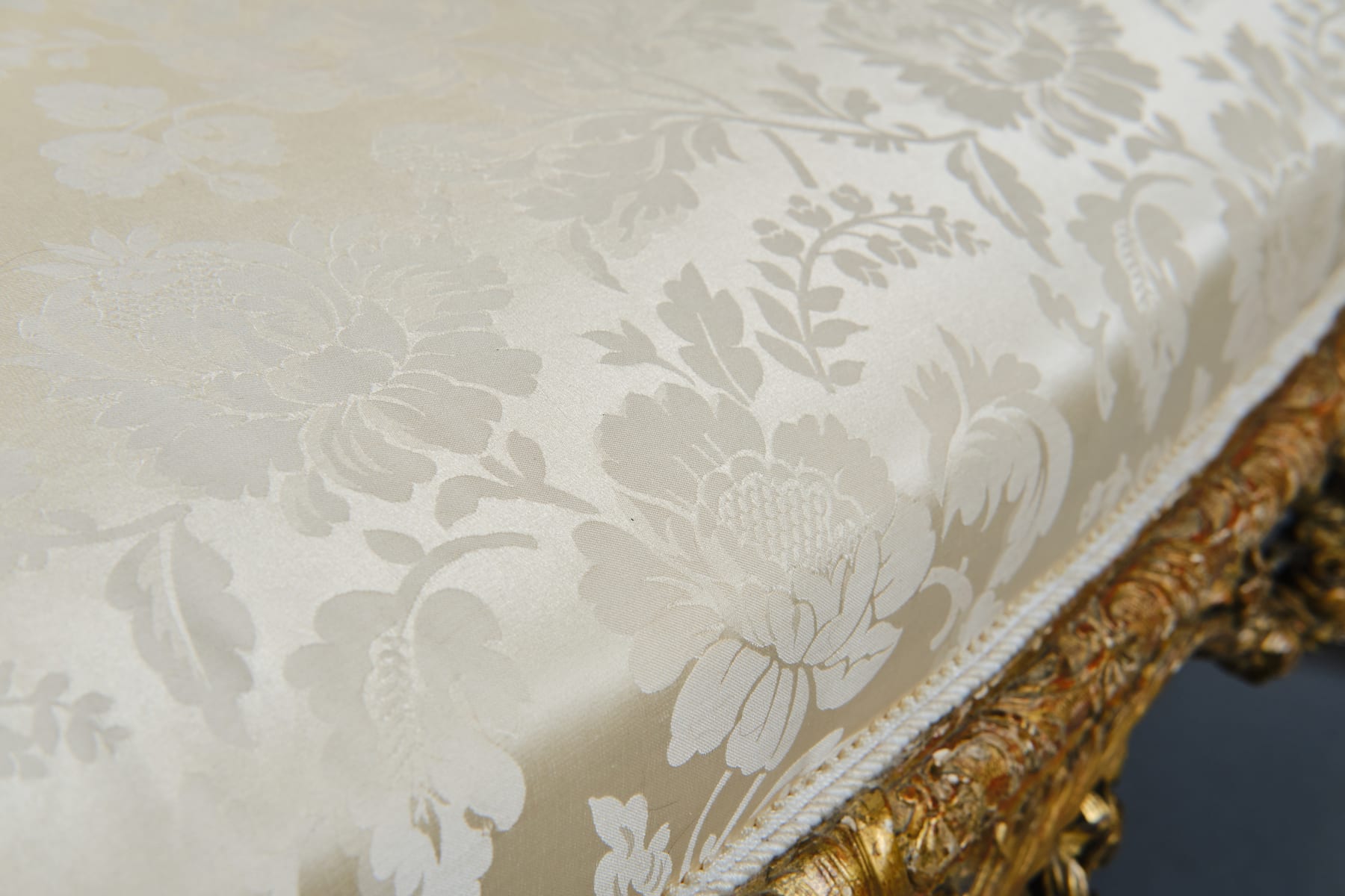 CARVED AND GILDED WOOD SOFA, FRANCE, 18th CENTURY, two-seater, mixtilinear layout and entirely traversed by relief carvings, with floral festoons, garlands, manly masks in the back uprights and stylized dolphins in the armrests with curly finials, upholstered in modern fabric with classical decoration, the back removable