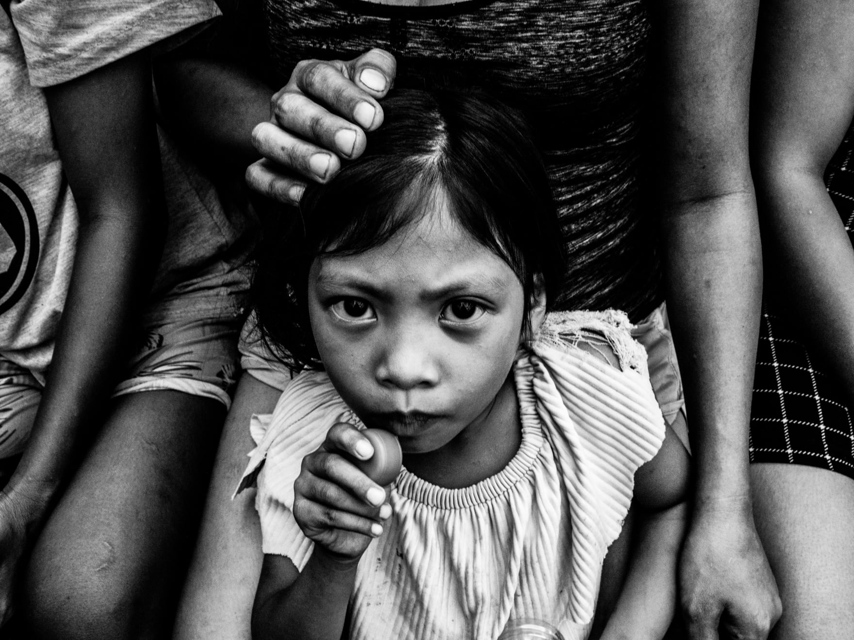 Xyza Cruz Bacani, Crystal Joy plays with a toy while sitting on her mother's lap in Smokey Mountain, 2020