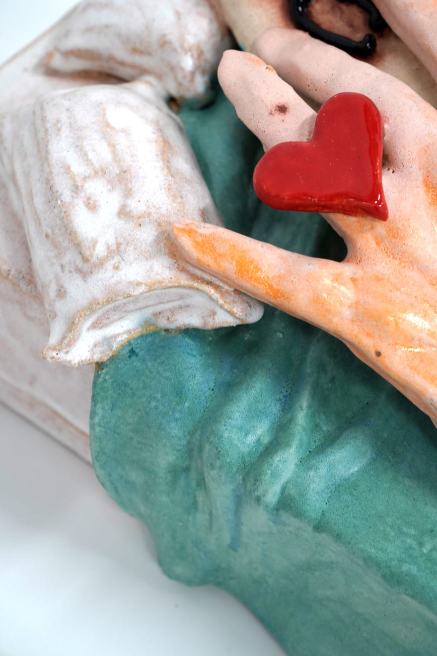 ceramic sculpture of a hand laying in a bed