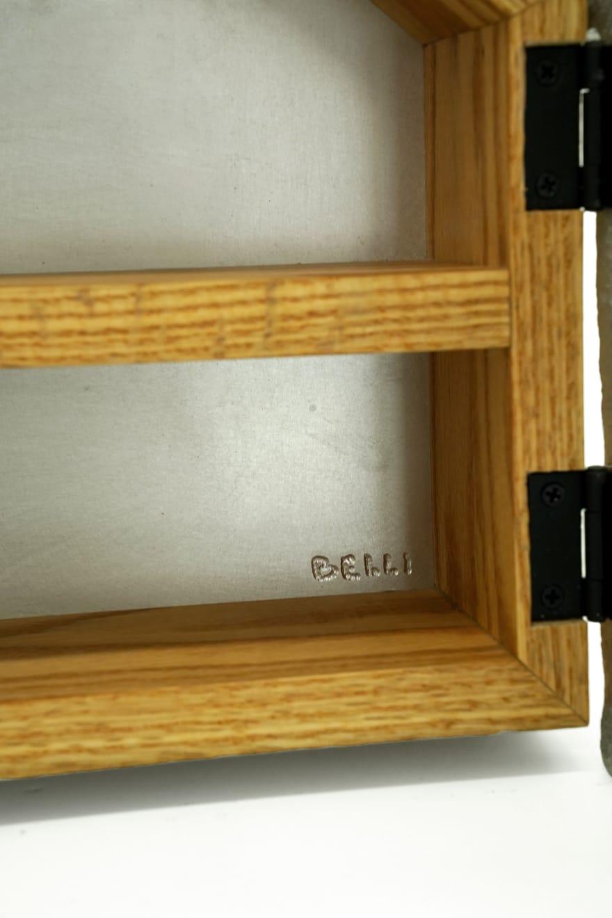 Wooden cabinet shaped like a house with metal cast on the front