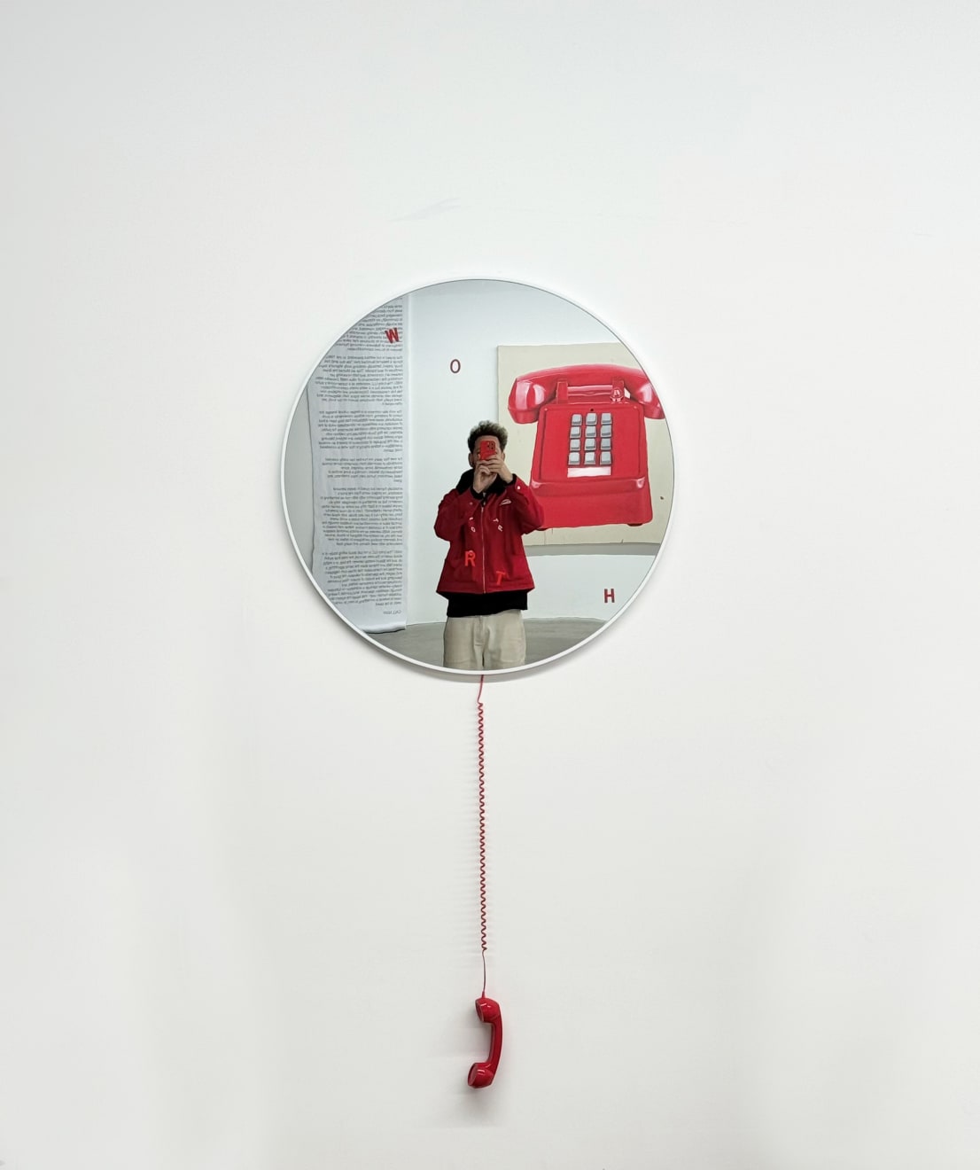 circular mirror with a red phone hanging from it