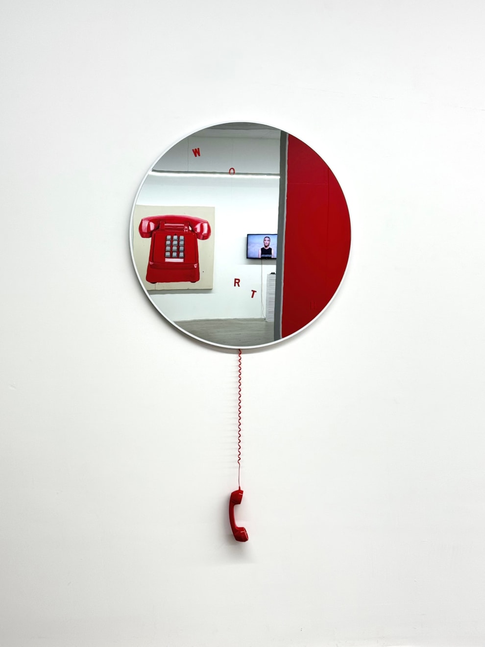 circular mirror with a red phone hanging from it