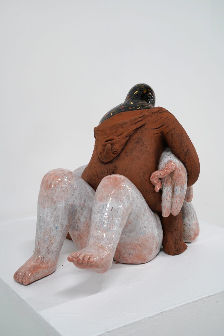 ceramic sculpture of a being sitting on top and stabbing another being
