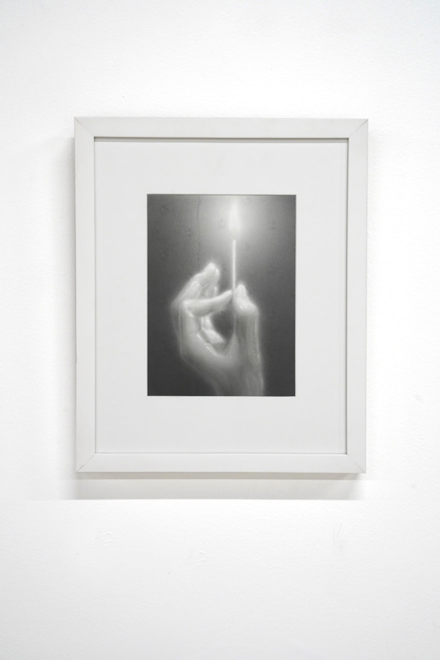 black and white charcoal hand holding a lit match, framed in white