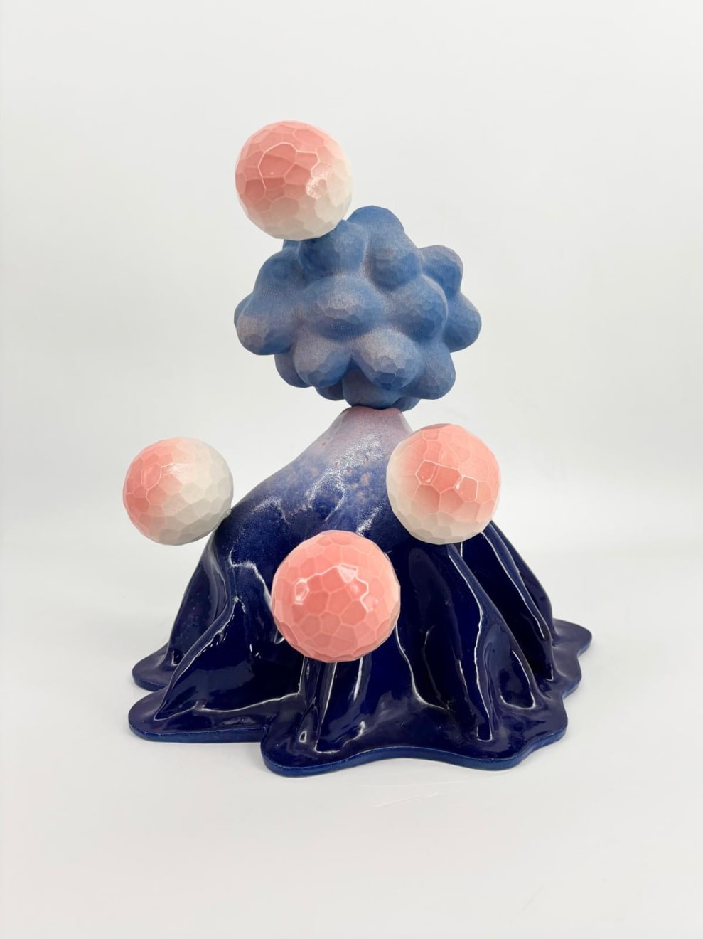 Volcano-shaped ceramic sculpture by Kartini Thomas with pink faceted spheres emerging from a glossy blue base, made of stoneware and porcelain.