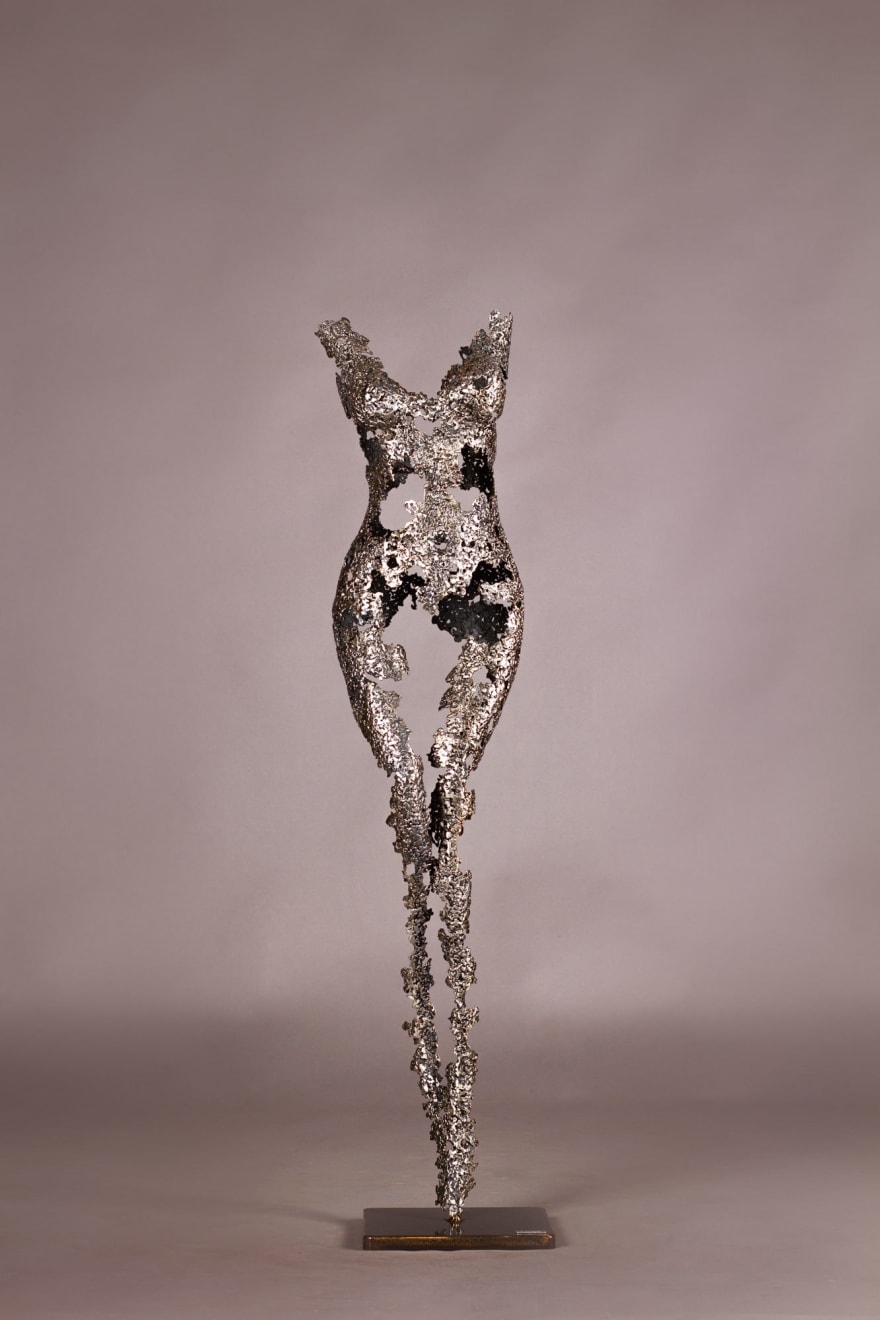 This slender, elongated sculpture is crafted with a high level of detail, where each piece of wrought iron is intricately shaped and assembled to form a delicate, almost lace-like texture.