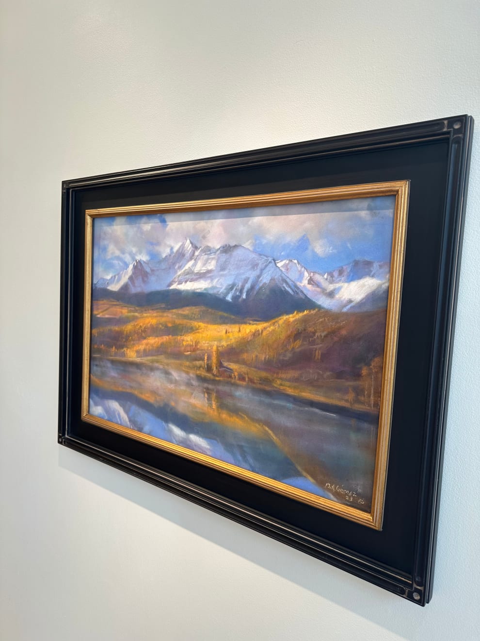 Pastel painting in a black frame of a mountain range with a body of water in front of it by Slate Gray Gallery artist Bruce A. Gomez