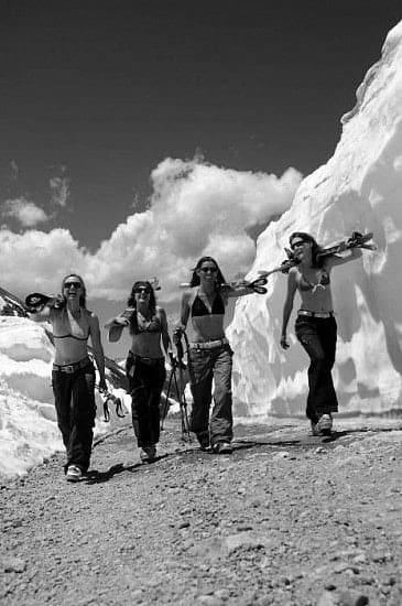 Black and white photo of four female skiers in bikini tops hiking their skis up ophir pass by slate gray gallery photographer Brett Schreckengost