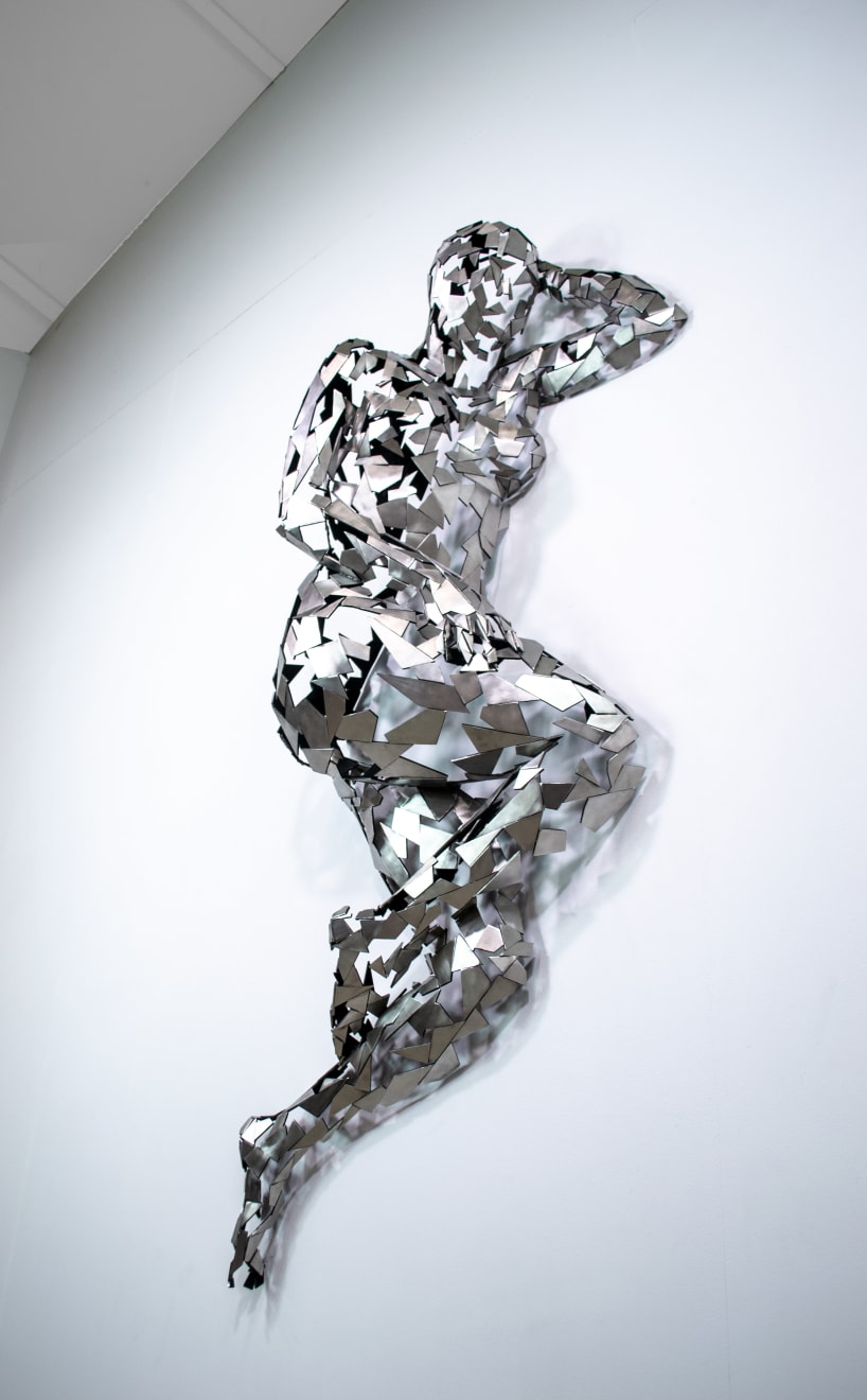 Stainless steel sculpture of a person laying on their side with their arm under their head by slate gray gallery artist David Davis