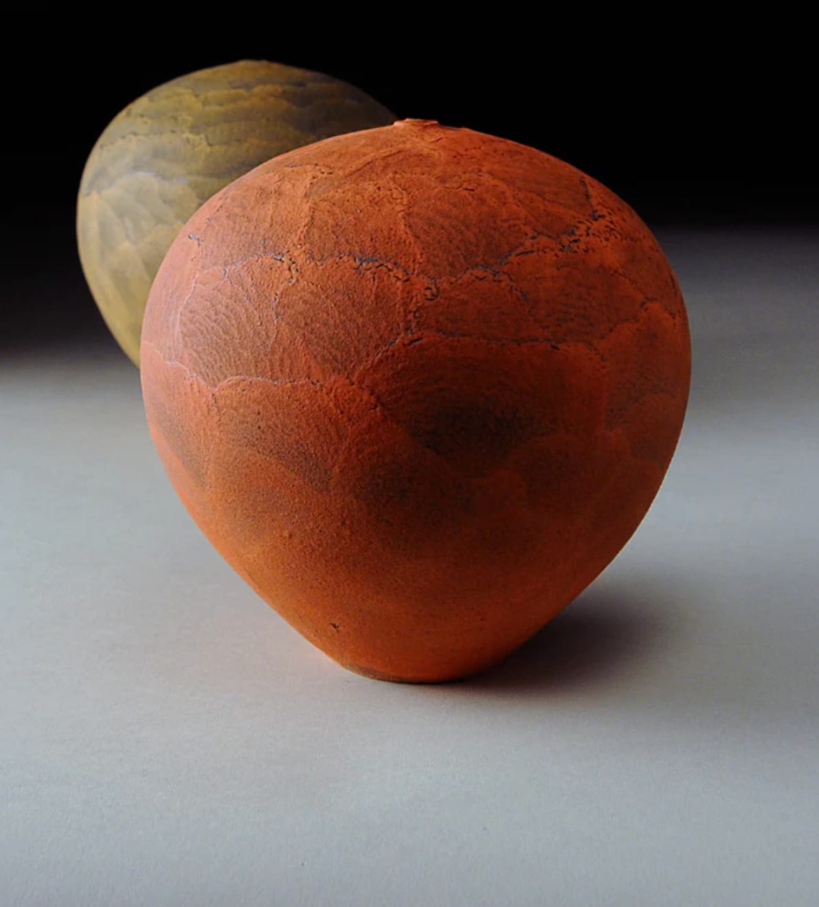 bright red earthenware vessel with one other vessel in the background by potter Nicholas Bernard