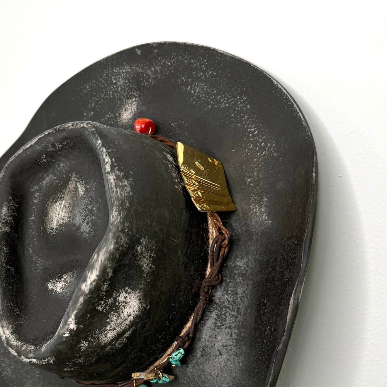 Brock DeBoer sculpture of a black cowboy hat with gold playing cards and bullet on the brim
