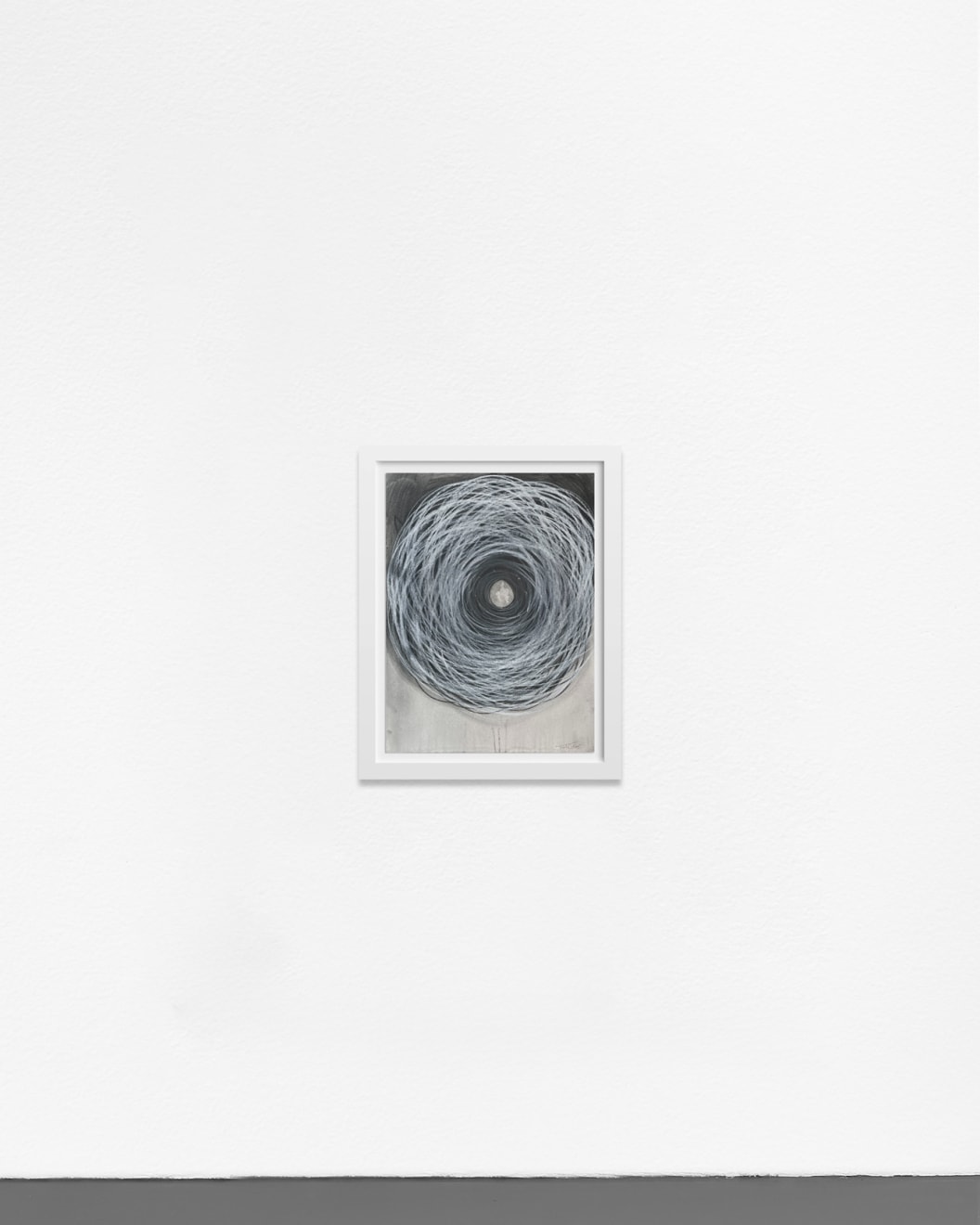 Ted Collier work on paper of vicious chaotic spiral in black in white charcoal framed in a white frame hanging on a white wall