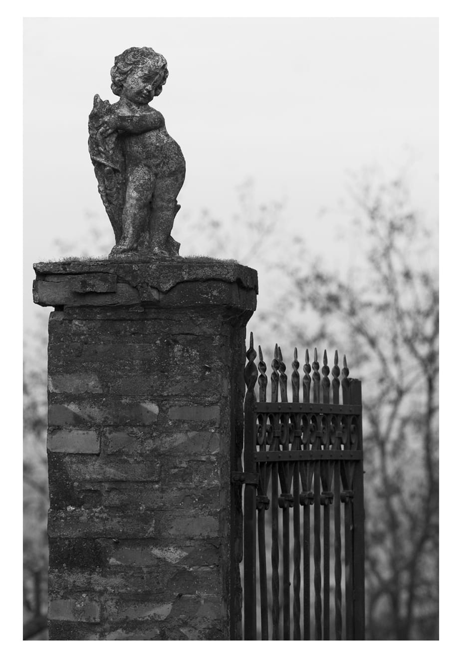 Black and white photograph of an old statue in the country side of Italy.