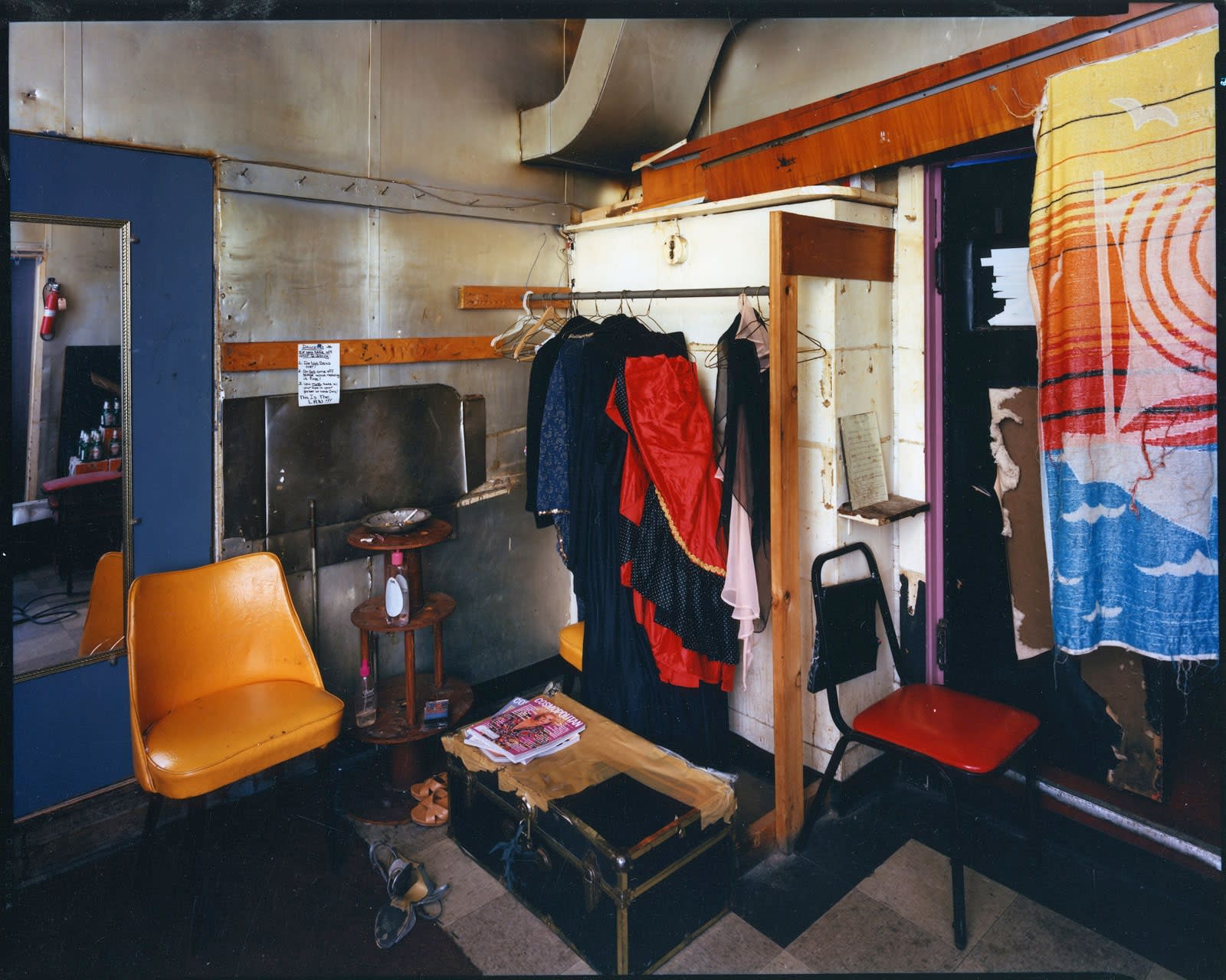 Bruce Wrighton Gold chair on left, in front of mirror, trunk on floor, clothes hanging from rod Tirage C-print d'époque 20 x 25 cm Dim. papier: 20 x 25 cm