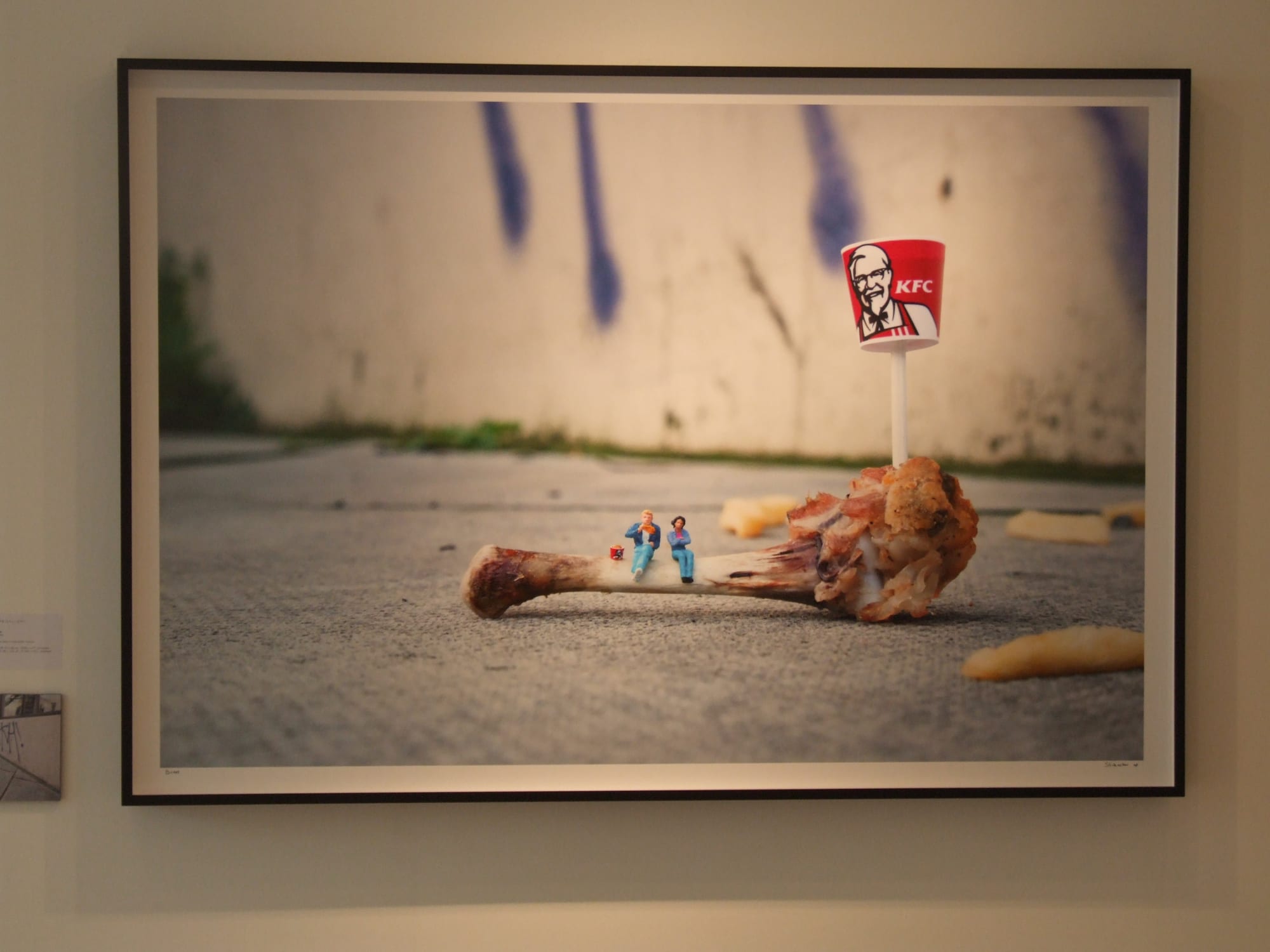 Slinkachu print hanging in exhibition.