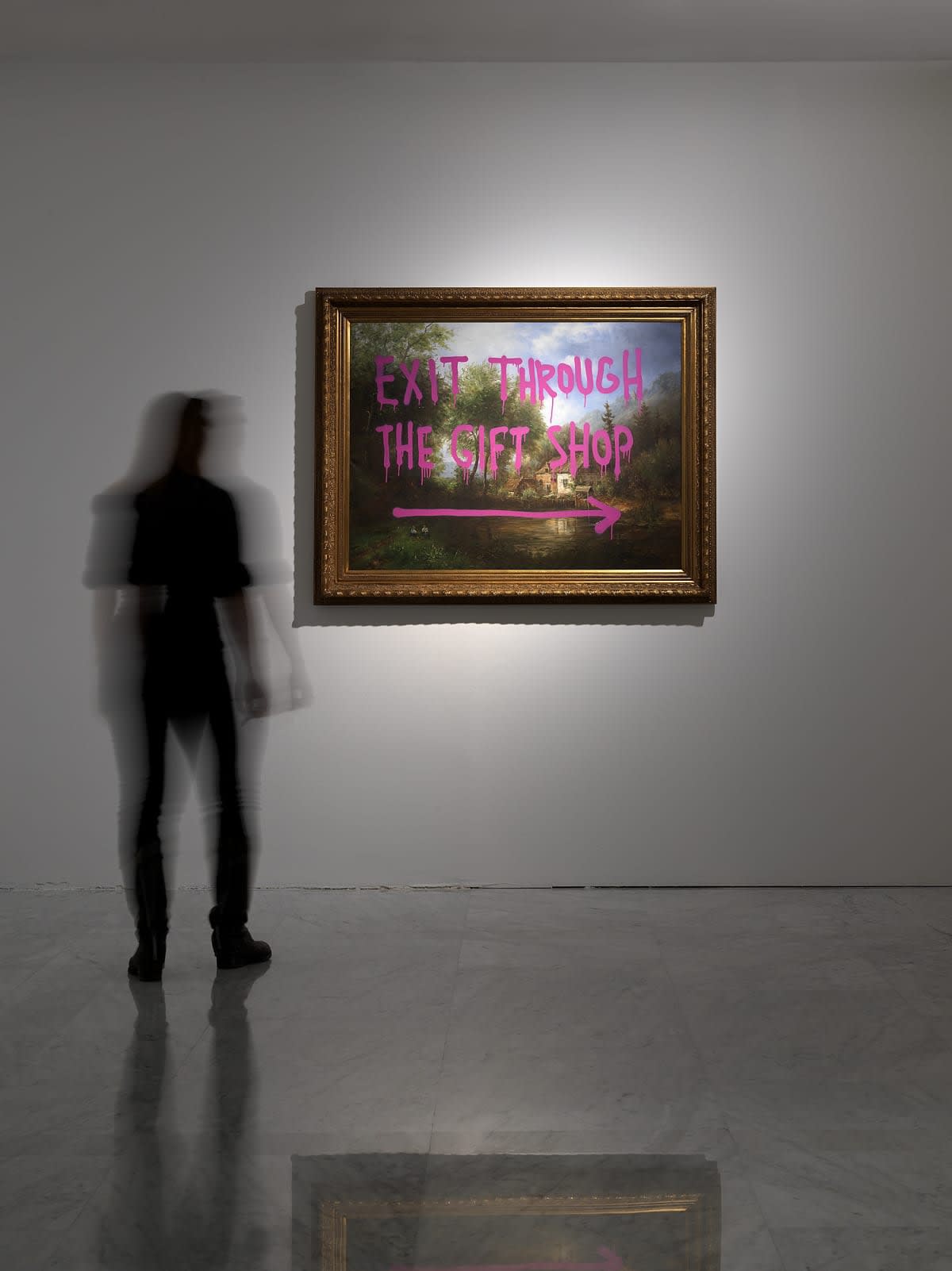 Banksy Exhibition installation, Print hanging on the walls. Blurred woman looking at print