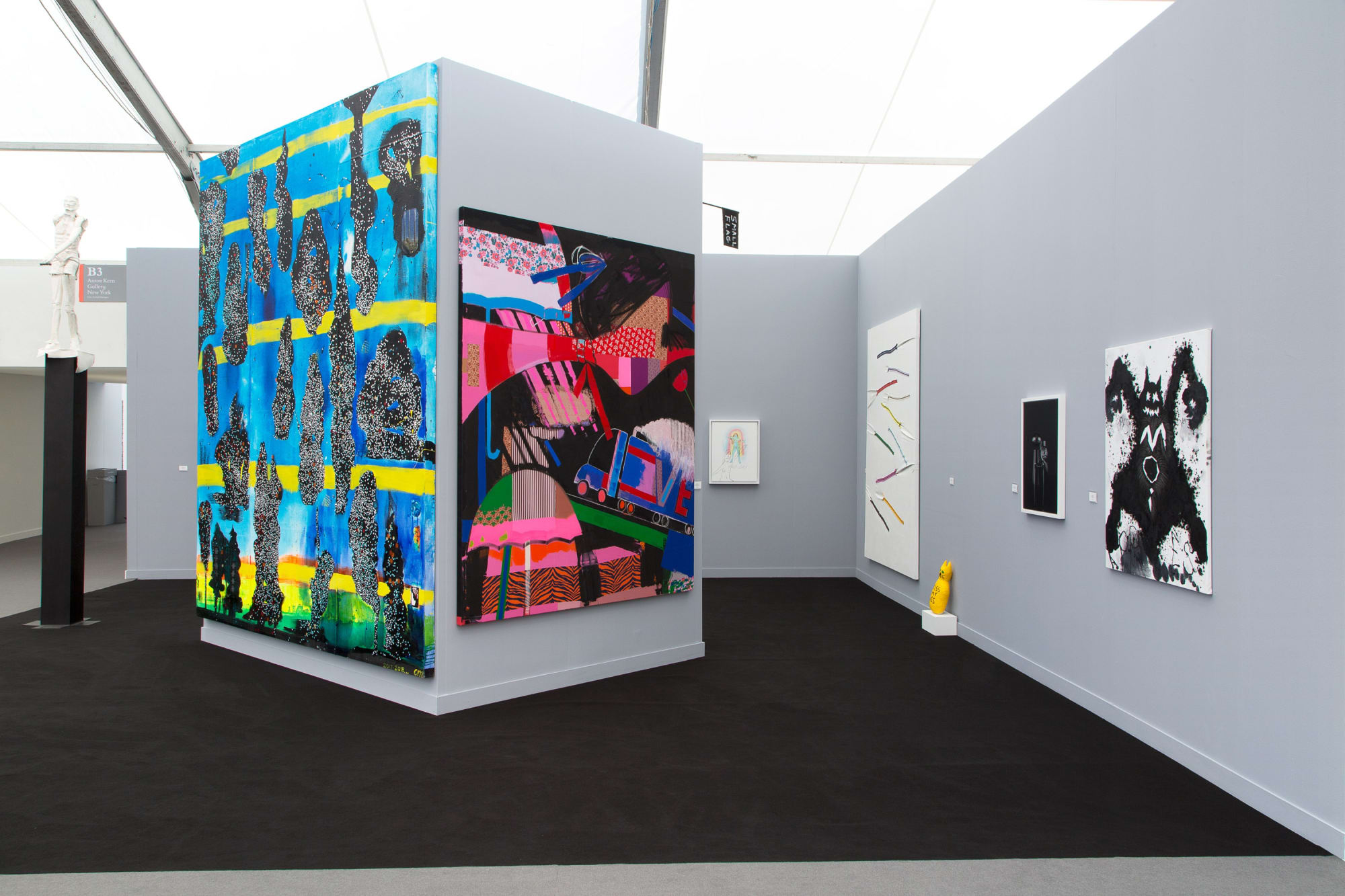 Installation view at the fair. Gray walls and works scattered among them. Many large paintings are shown.