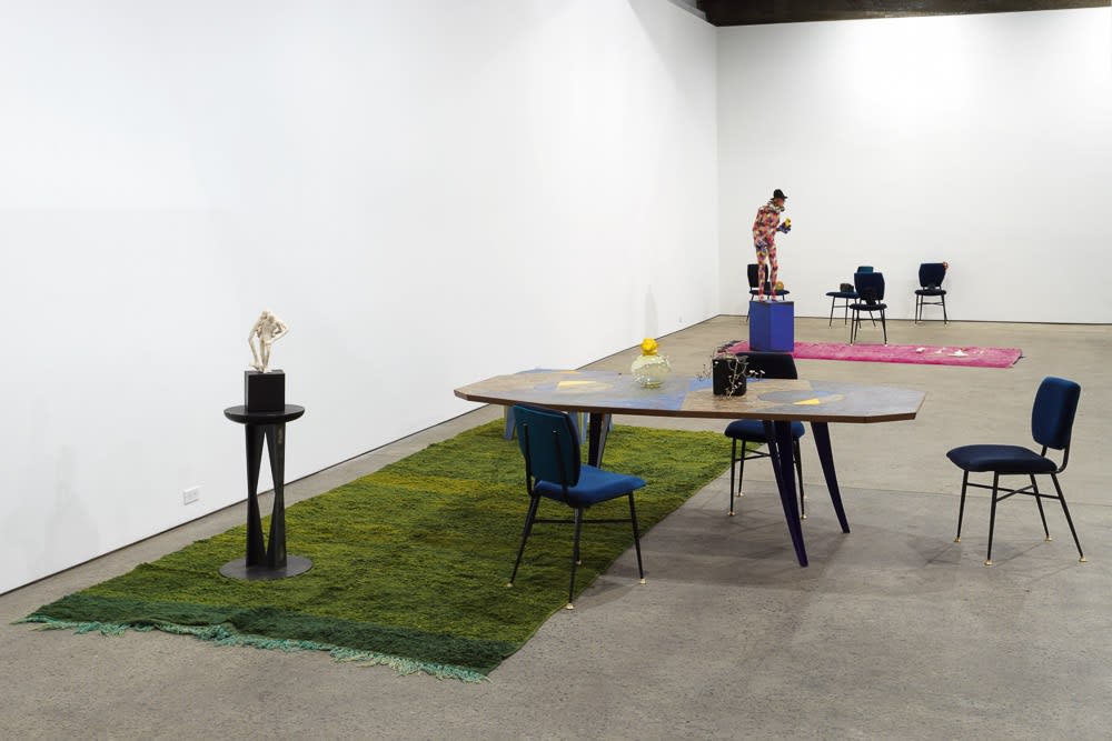 Installation view of Francis Upritchard and Martino Gamper's collaborative show. Gamper table and chairs in front of green carpet.
