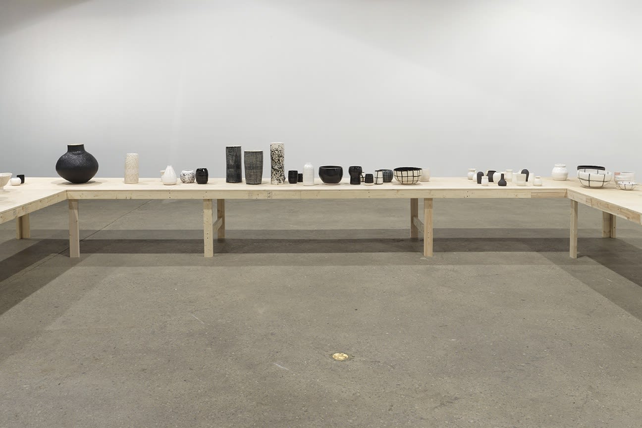 Installation view of Shio Kusaka's second show at Anton Kern Gallery, featuring a large collection of unique porcelain pots. Shades of black, grey, white pots.