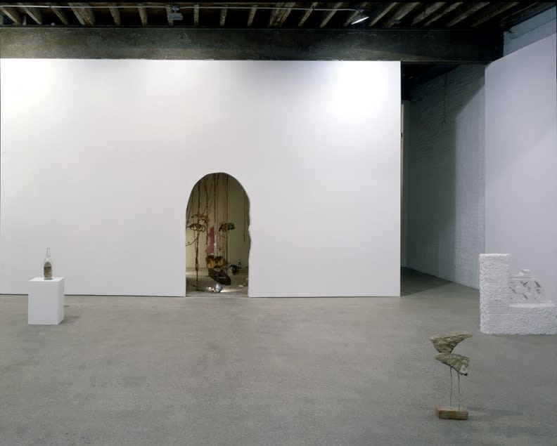 Installation view of Richard Hughes' first solo show in the U.S. Stones, paint buckets, worn out shoes, a dirty mattress, and rotten barrel planters occupy the gallery installation. Mixed-media work and other objects.