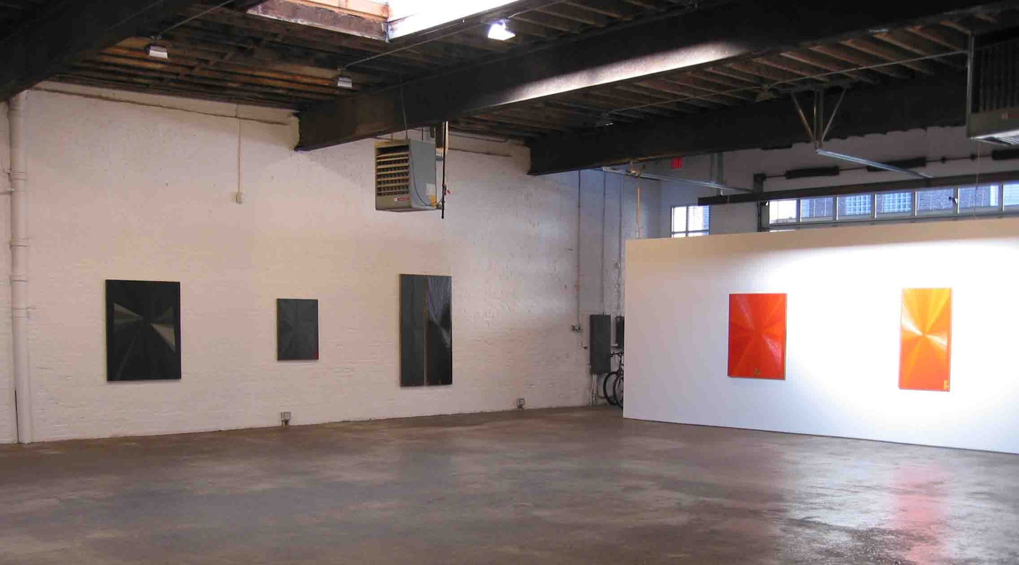 Installation view of Mark Grotjahn's first show at Anton Kern Gallery, featuring a series of bold geometric paintings. A few paintings shown.