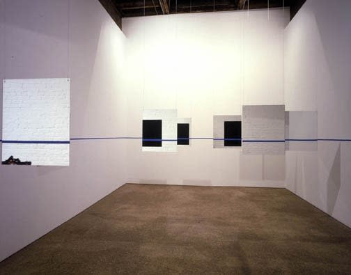 Installation view of Edward Krasinski's first solo show in the United States, featuring a site-specific installation of hanging mirrors and a roll of blue masking tape. The back gallery featured.