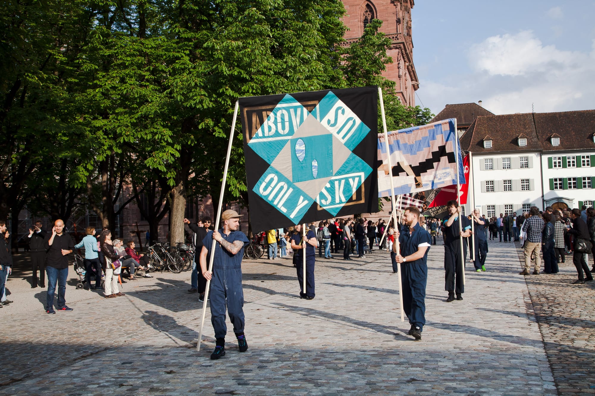 Installation view of Lara Schnitger's show at Basel Parcours, featuring a large body of works as well as a procession through Mezzeplatz. "No Religion" being held high by two marchers.