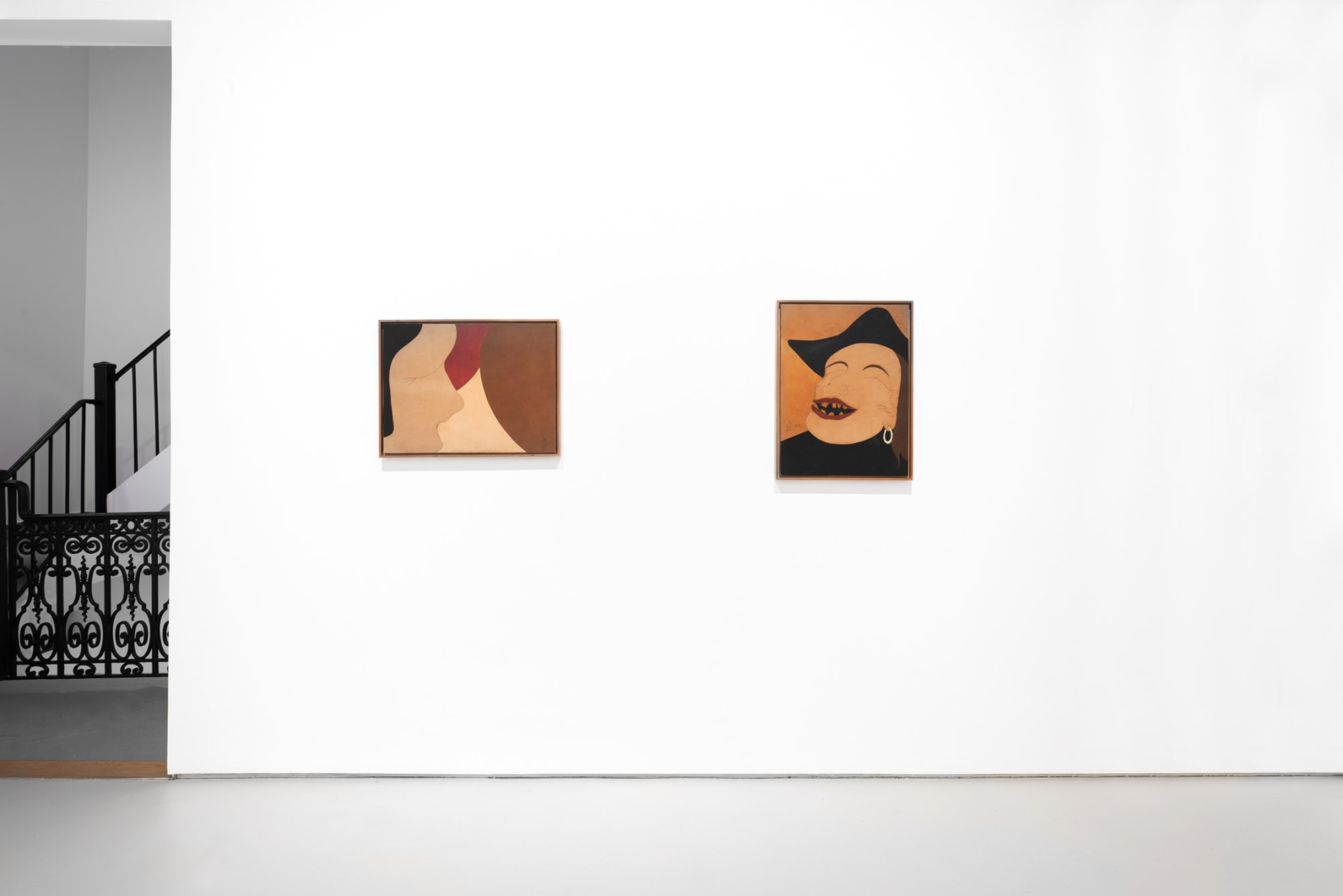 Frontal view with wall holding two paintings; left side of image includes metal railings for stairway.