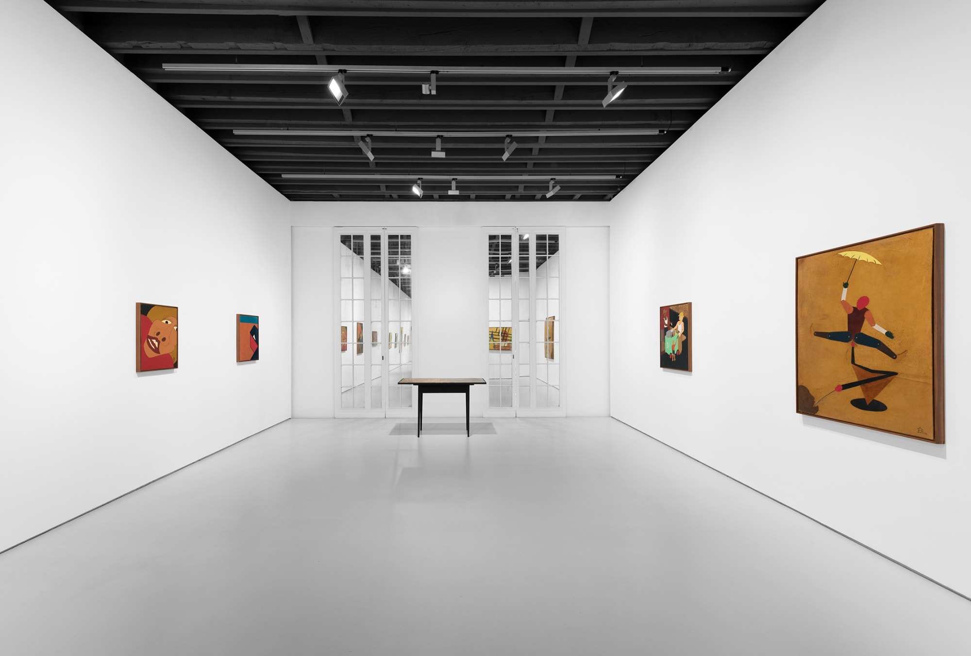 View with glass doors, dark table, and four paintings.