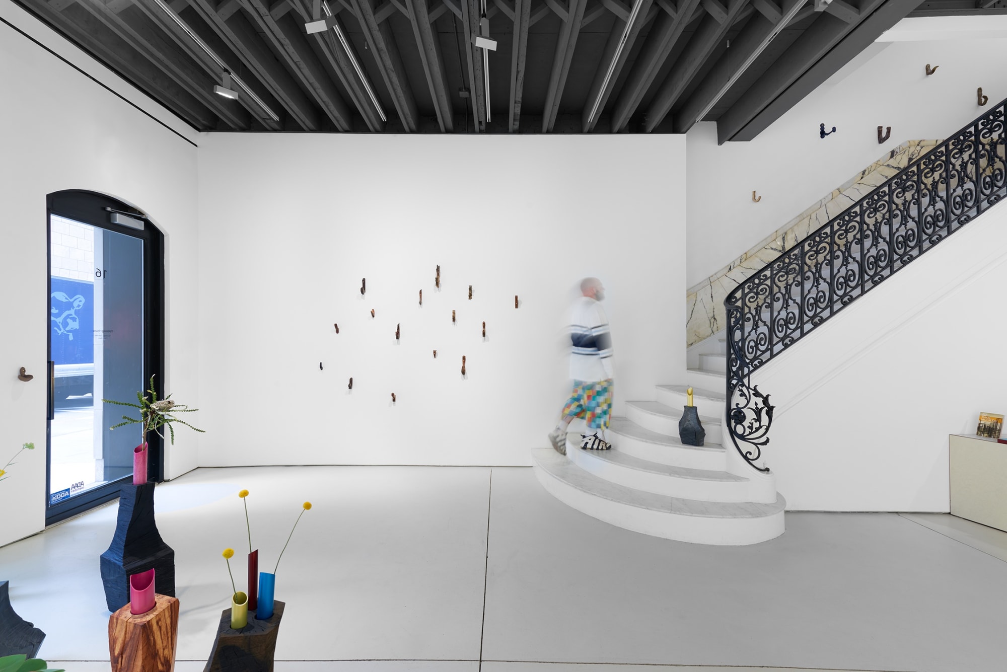 Installation view of the 2023 exhibition “Martino Gamper: I am many moods” with view of white floors, stairs, walls, artworks and ceiling.