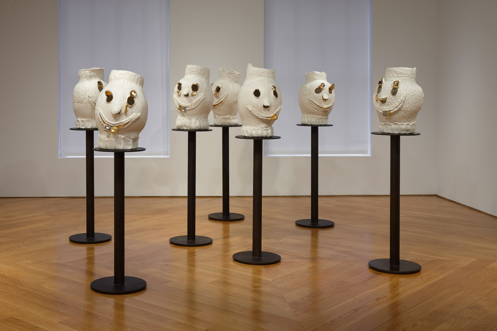 Installation view of Dan McCarthy's exhibition '7 Bangers', a group of seven ceramic sculptures with faces. Straight on shot of seven faces.