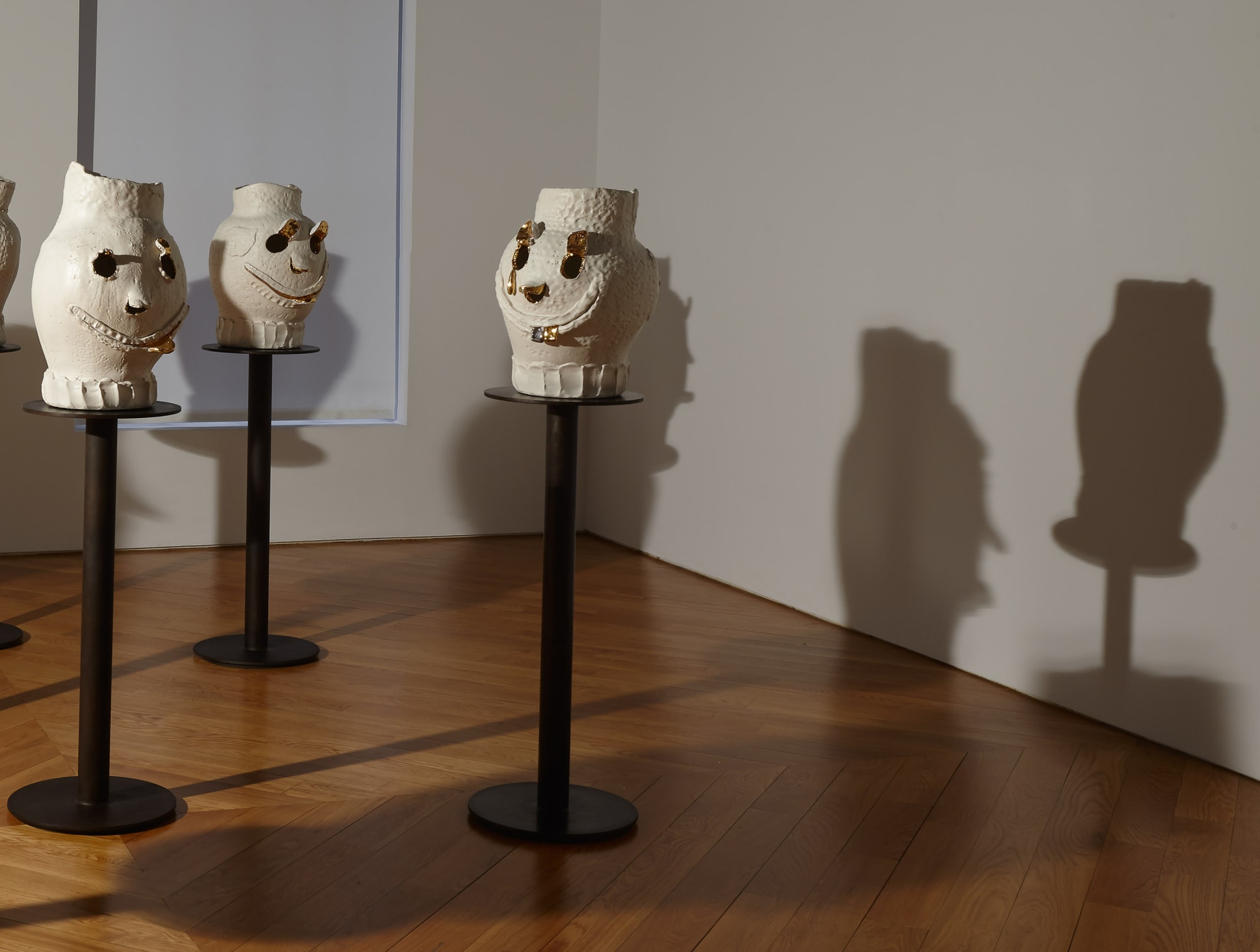 Installation view of Dan McCarthy's exhibition '7 Bangers', a group of seven ceramic sculptures with faces. Two faces featured.