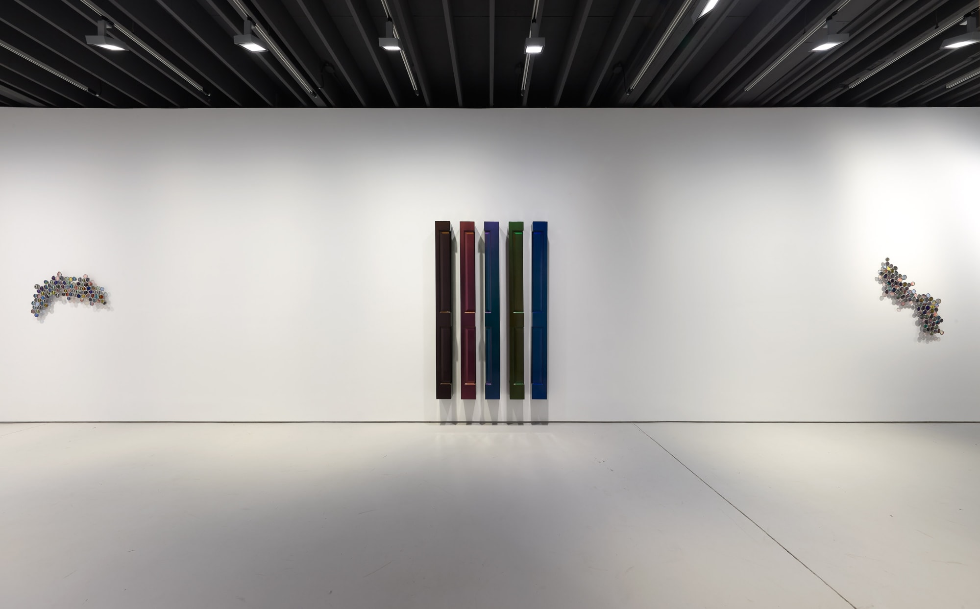 Jim Lambie's installation at the gallery 'Skin Shape' featuring ladders and other works. Lambie engages with other household structures. Here, Lambie's wooden doors hang on the gallery walls.