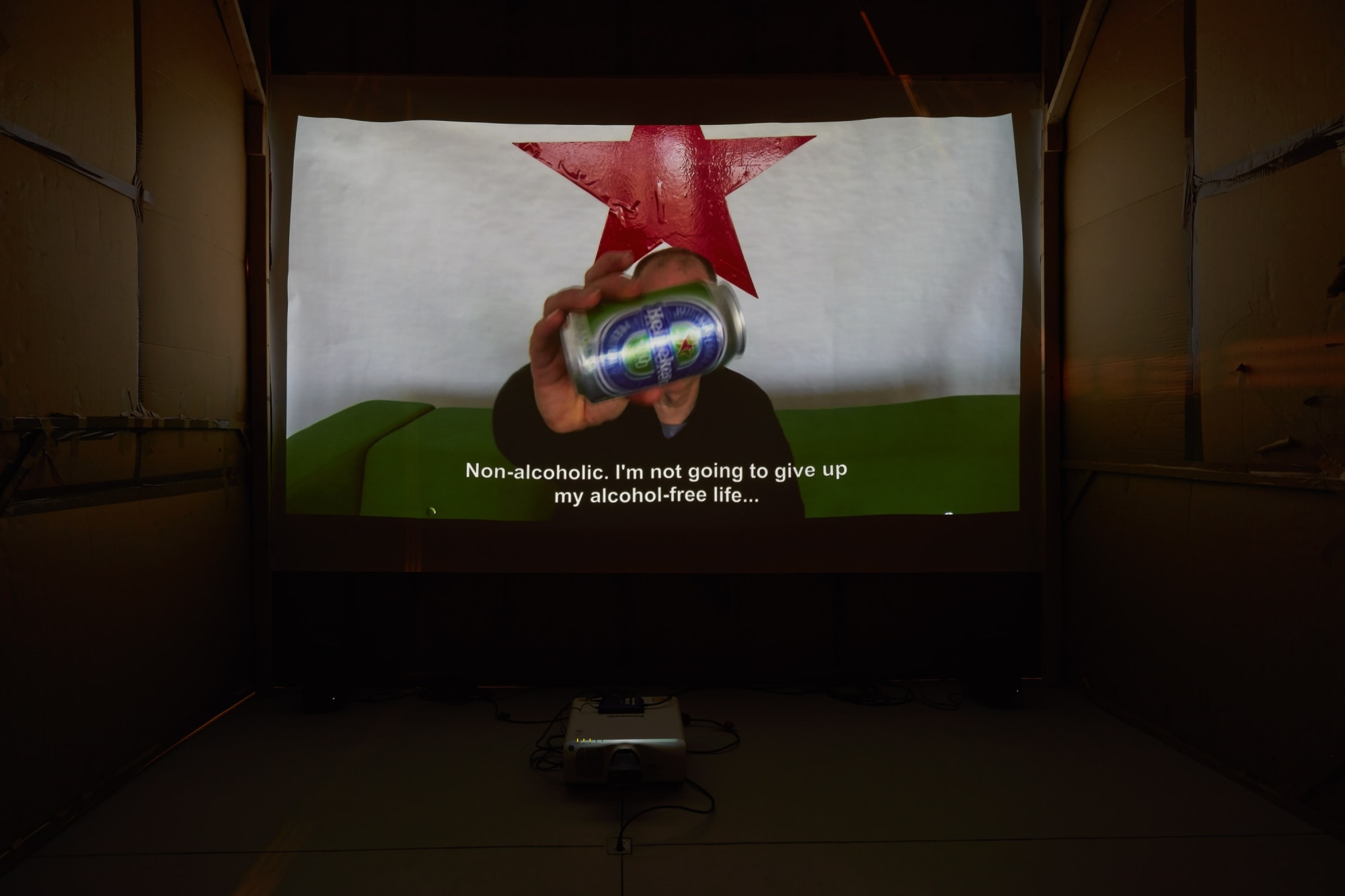 Installation view of Erik van Lieshout's exhibition at the gallery 'BEER' -- featuring an immersive Heineken installation and new collages. Image shows video installation.