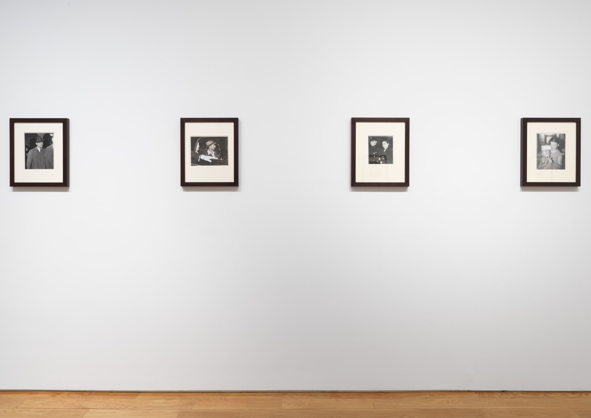 Installation view of Weegee photos, showing two dark-framed photos.