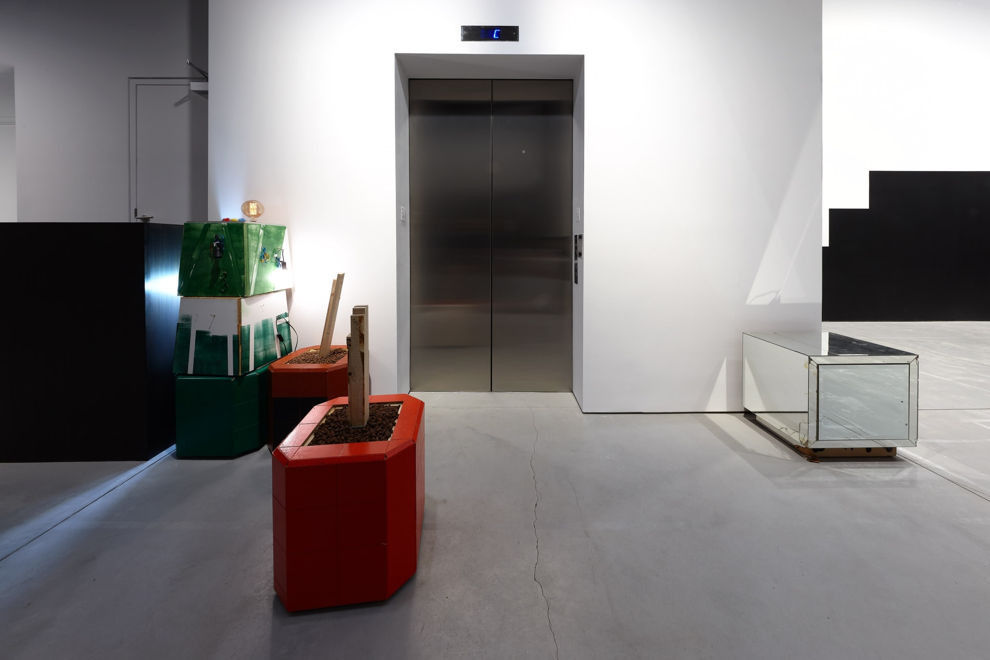 Installation view of Manfred Pernice's exhibition of sculptures involving architecture language. Red table visible.