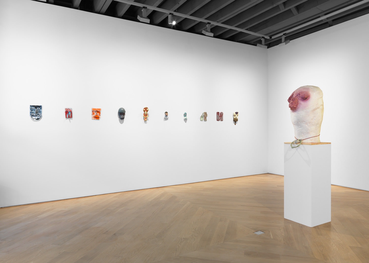 Installation view of Nicole Eisenmen show titled Faces featuring large sculptures and cast faces. Many works presented.