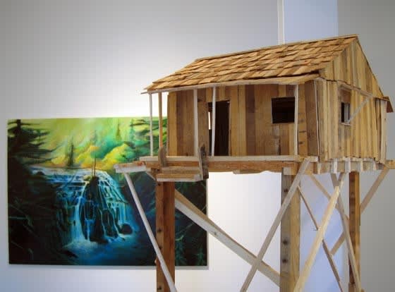 painting hanging on a wall behind a wooden model of a shack