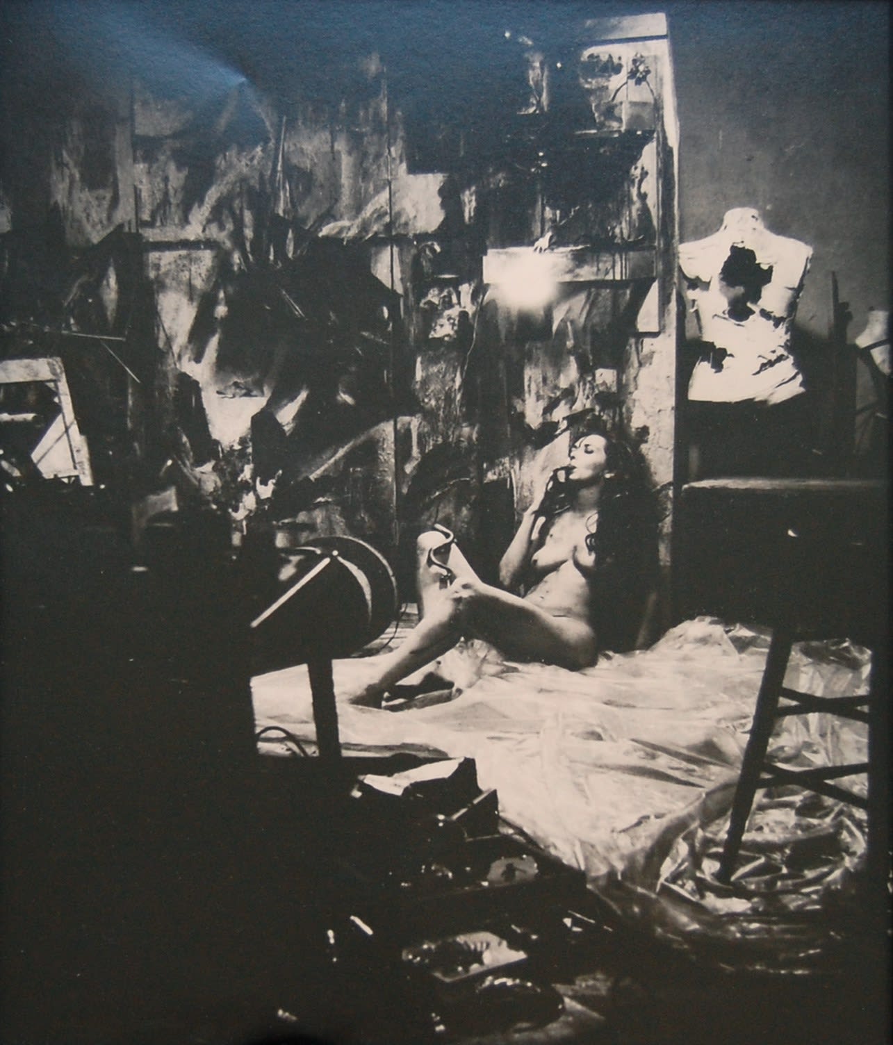 Black and white photograph of Carolee Schneemann sitting naked on floor with her eyes closed