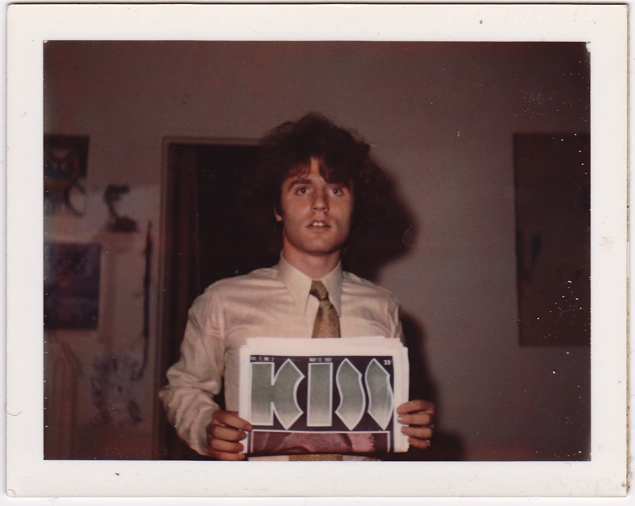 Polaroid of man wearing a tie and holding a Kiss album
