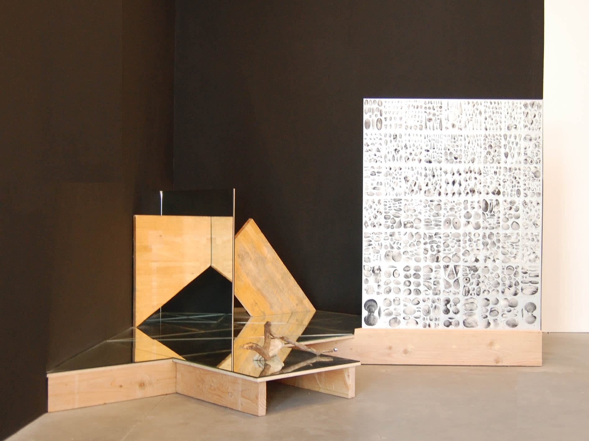 Wood and mirrored sculpture sitting on the ground in a corner