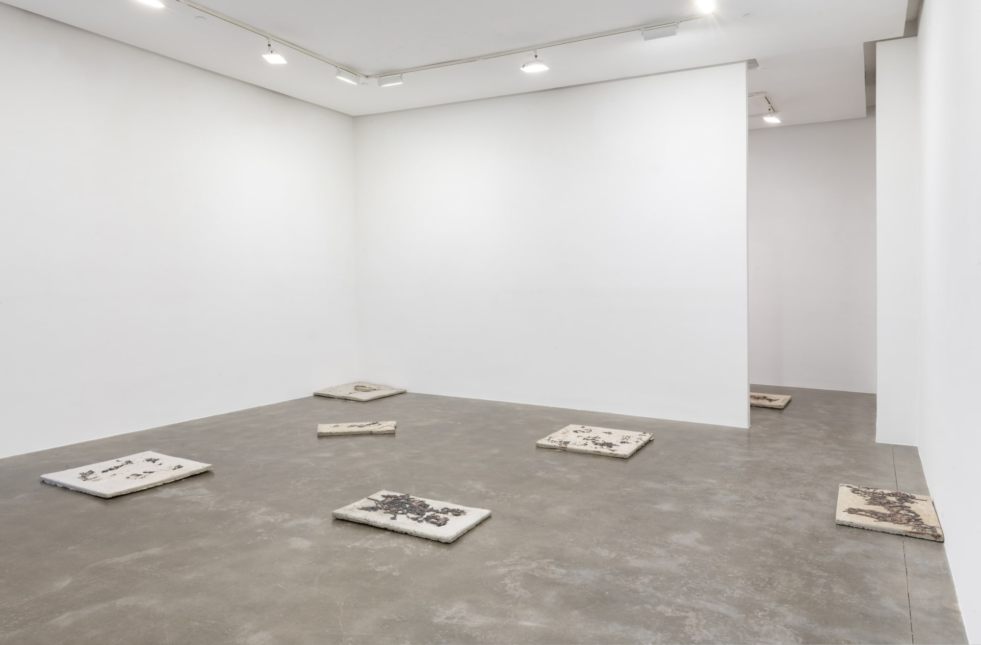 Installation view of Susan Inglett Gallery with concrete and bronze works by artist Wilmer Wilson IV scattered on the floor