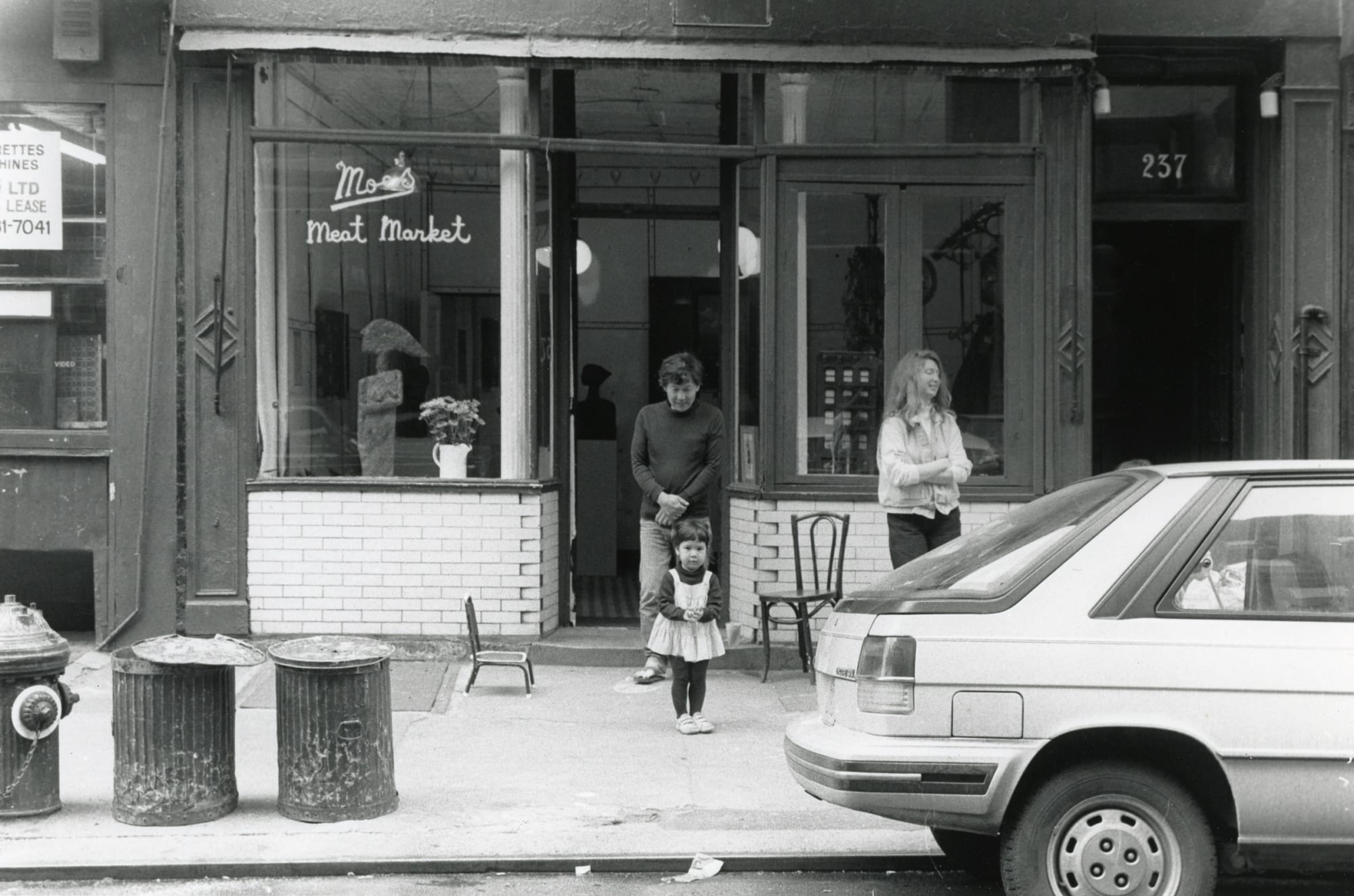 Black and white photograph of a man, woman, and baby standing outside of Moe's Meat Market