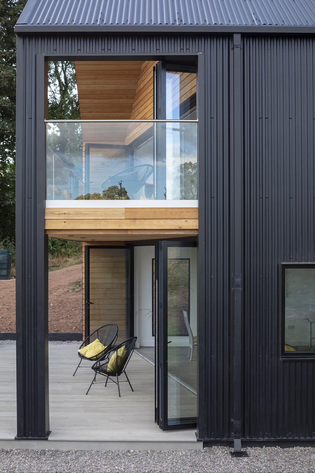 Barn House, with its black corrugated cladding, is cut into a farmland hillside.