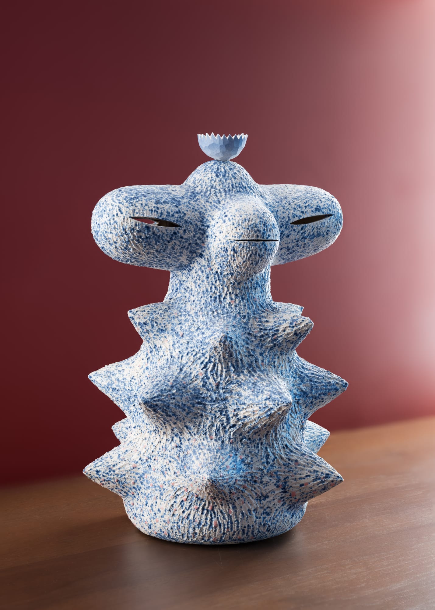 Ceramic sculpture titled Baby Mega Space Monkey (2025) by American artist Kartini Thomas, in blue and white speckled textures, displayed on a wooden surface.