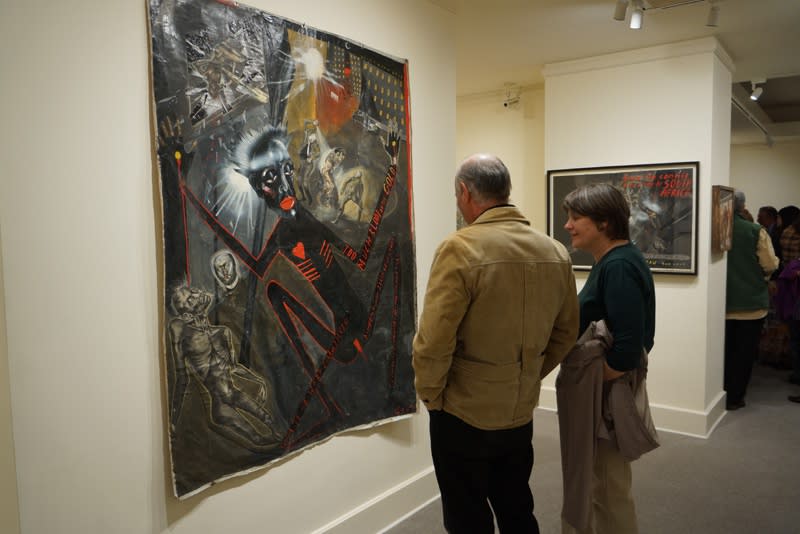 Photograph of visitors studying Sue Coe's "Welcome to the City of Gold," at the opening of the exhibition "Mad as Hell," 2012