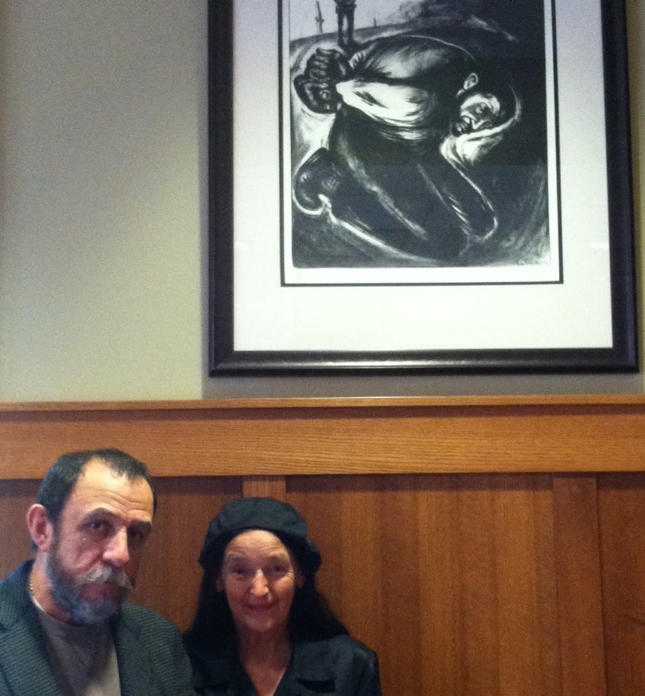 The artist and Joe Segura stand in front of an artwork that used Segura as a model